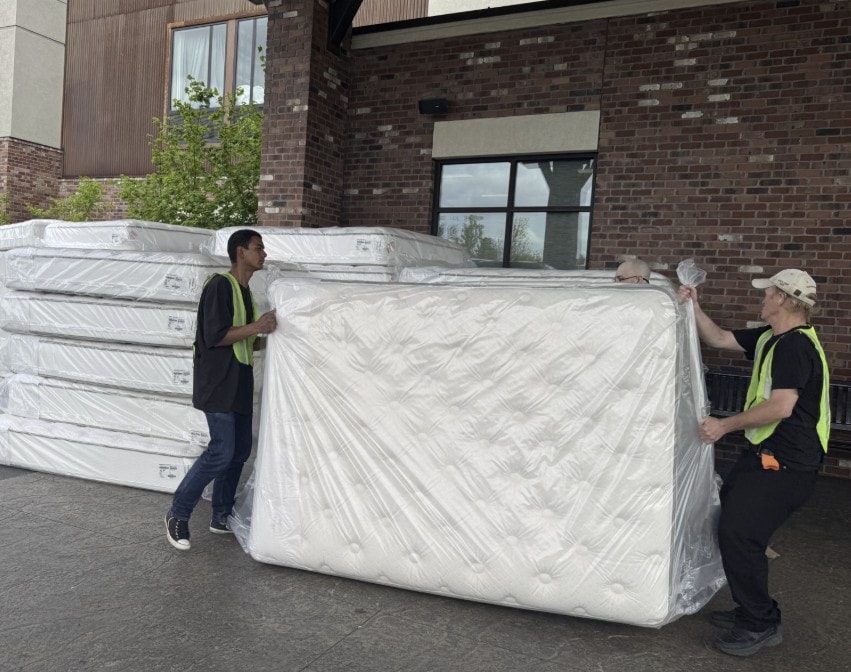 Spencer Restoration Services crew delivering new wrapped mattresses outside a hotel